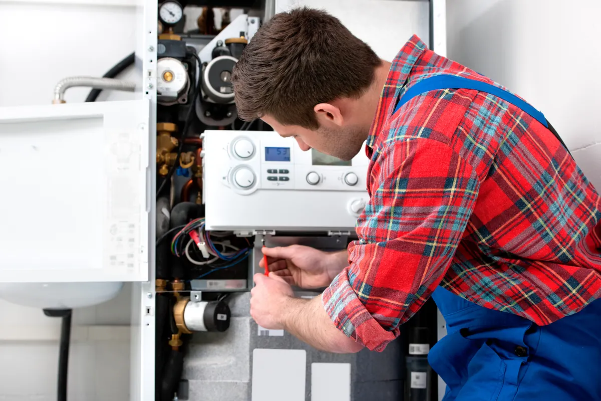 Heating technician servicing circulator pumps and zone controls on a residential boiler in Nassau County