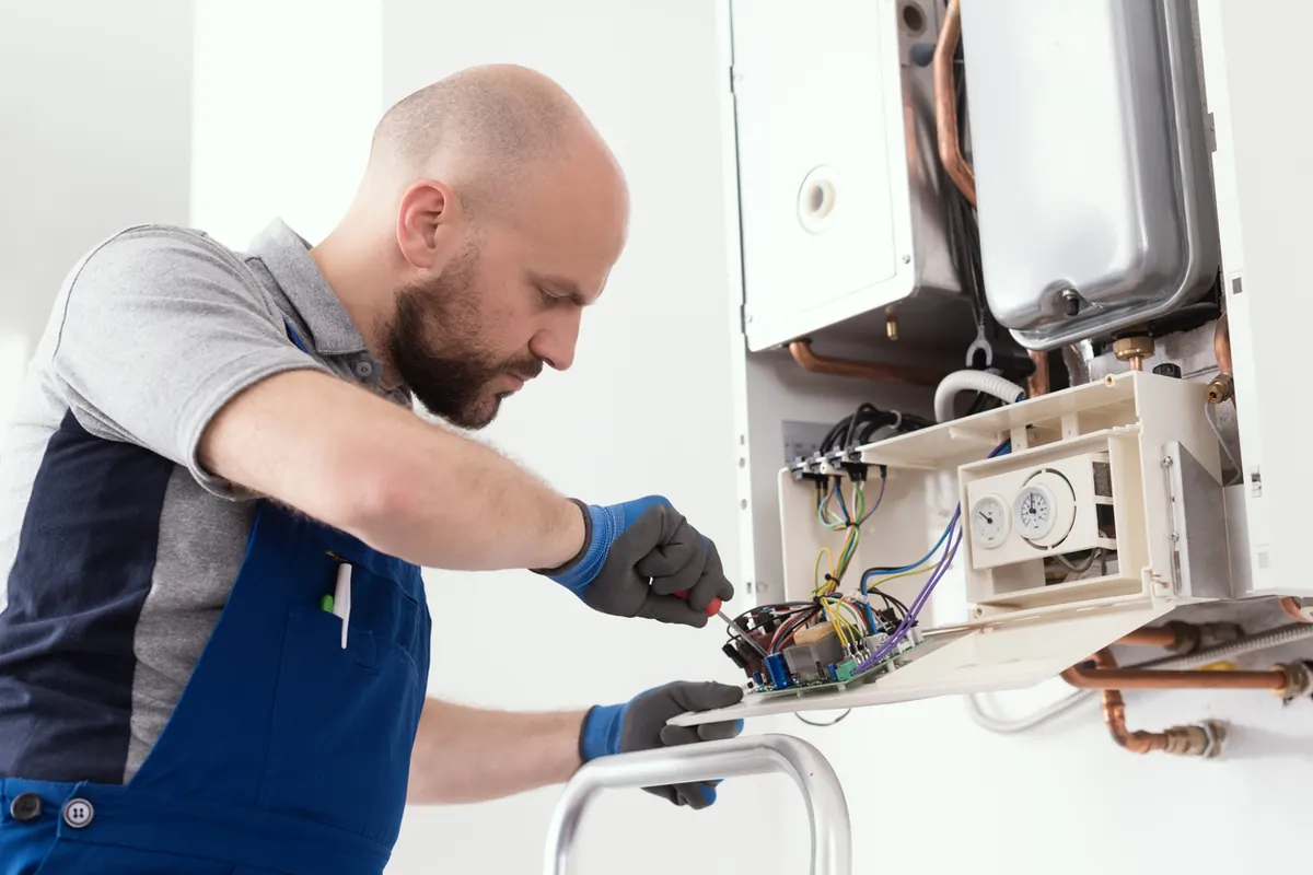 Licensed technician repairing a boiler control board in a Hicksville, NY home