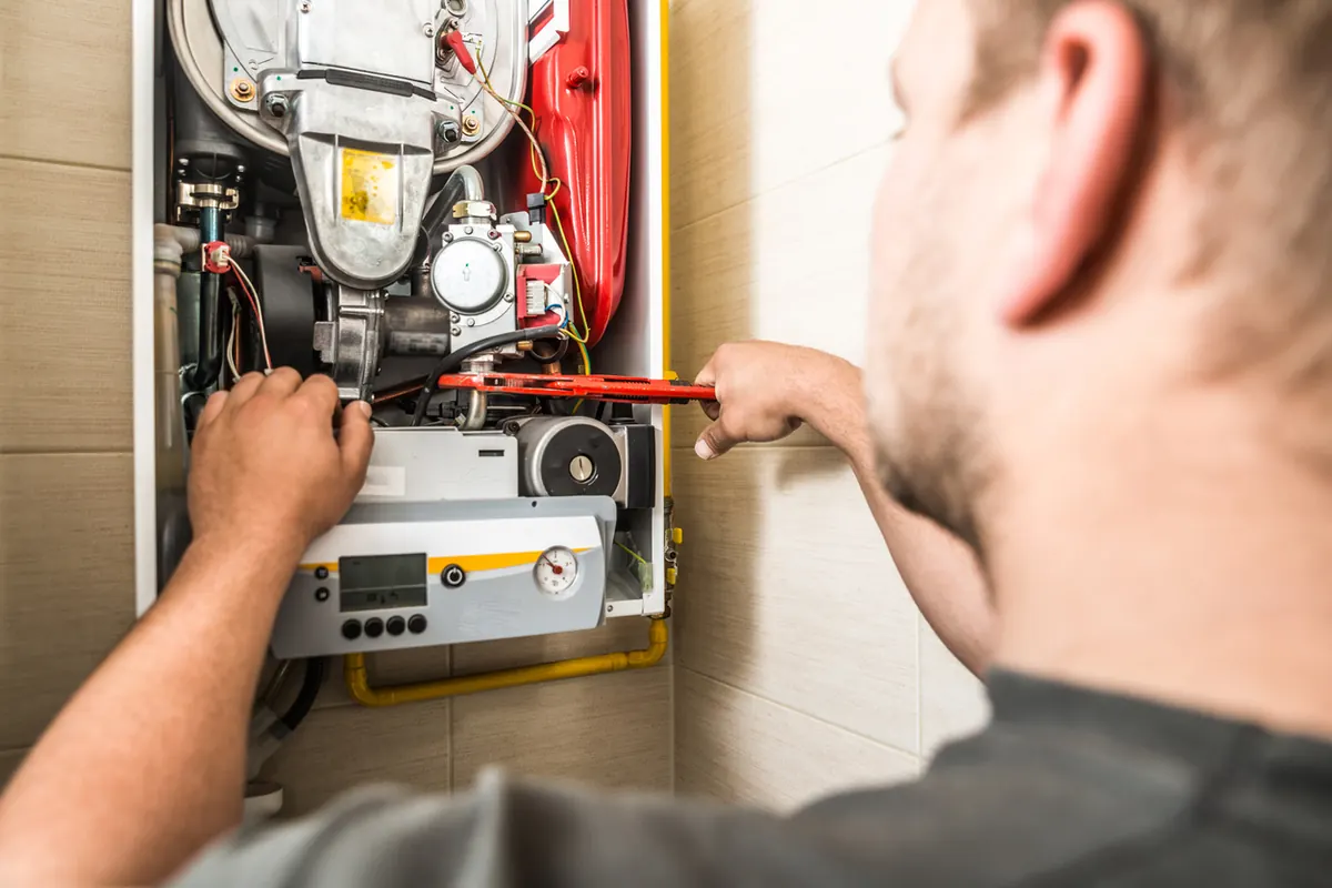 Technician adjusting a burner assembly on a residential heating system with a wrench